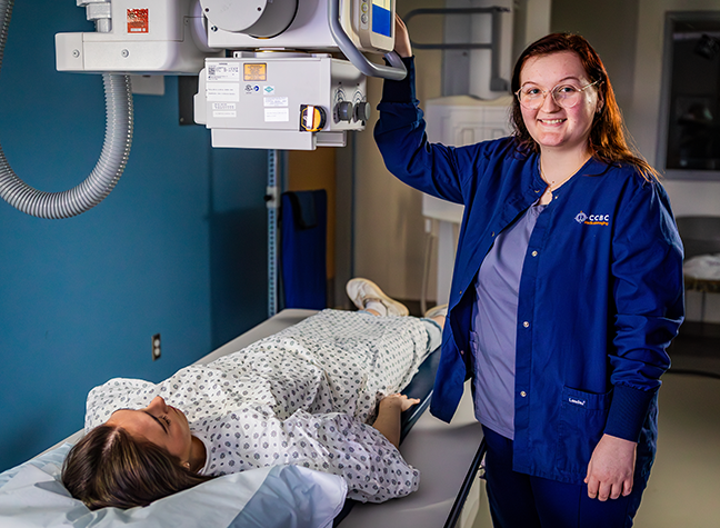 Female radiography student using equipment on patient