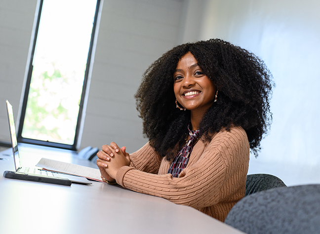 Simbo Sitting at a desk smiling at the camera